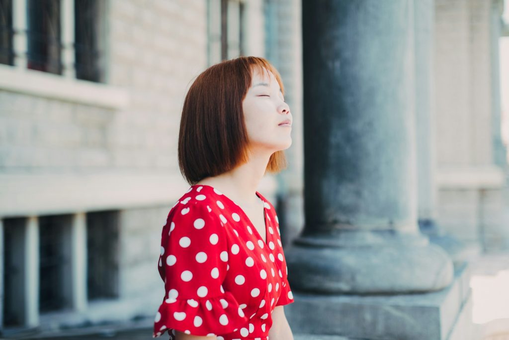Woman sitting outdoors with eyes closed, relaxed in the sun